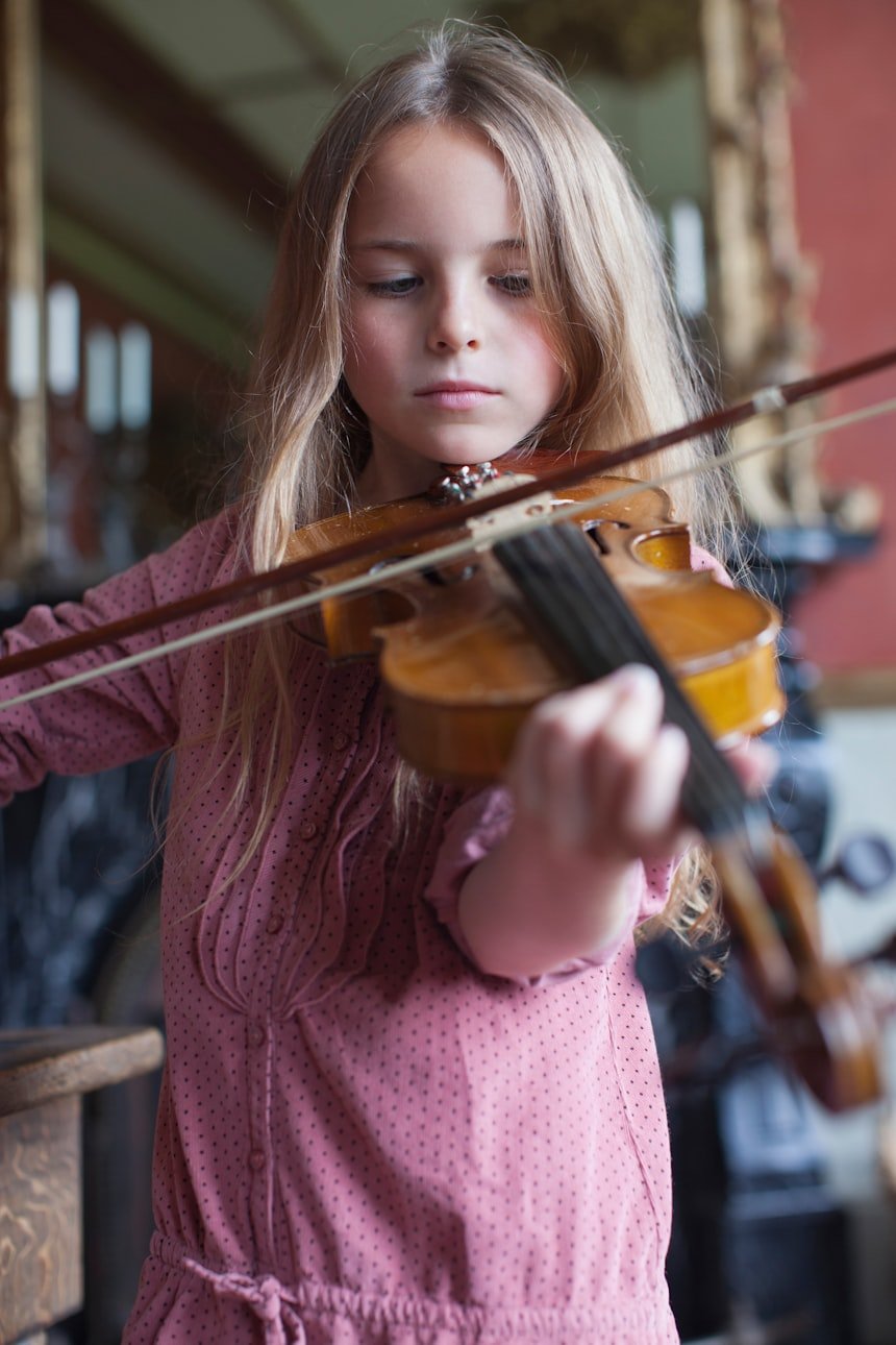 Little girl playing violin in a room &mdash; young student focused and engaged