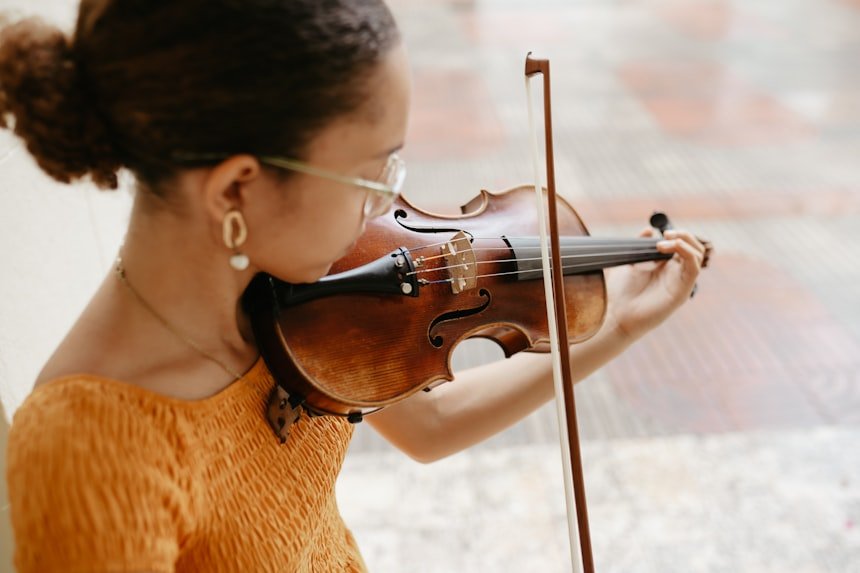 Woman in orange dress playing violin outdoors &mdash; advanced performance
